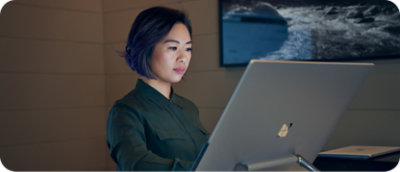 Osoba s krátkymi vlasmi pracuje v počítači v slabo osvetlenej miestnosti.