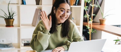 A woman waving at a laptop.