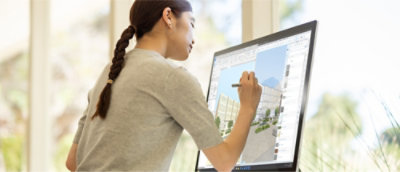 Une personne qui utilise un stylet pour concevoir un modèle de bâtiment en 3D sur un grand ordinateur à écran tactile.