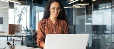 A woman in a red shirt and glasses using a laptop.