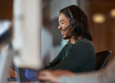A person wearing a headset and looking at a computer