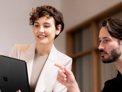 Two people collaborating while reviewing content on a laptop screen.