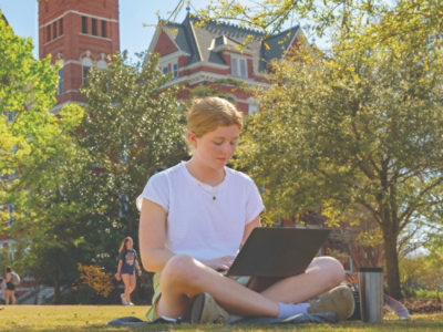 A person sitting on the grass with a computer