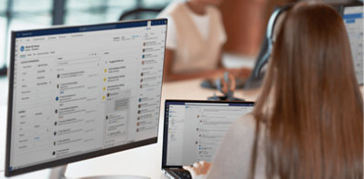 Een persoon die aan een bureau werkt met een laptop en een desktopmonitor.