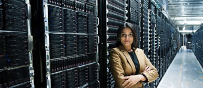 אדם בלבוש עסקי עומד כשזרועותיו שלובות בחדר שרתים, מאוגף בשורות של מדפי שרתים.