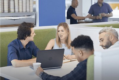 Vier Personen sitzen an einem Stand und unterhalten sich