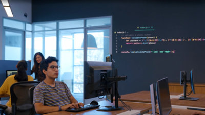 Person sitting at a desk, working on a computer in an office space. 