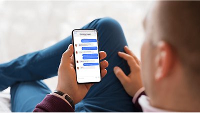 A person holding a mobile phone displaying a text conversation