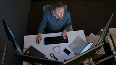 A person working with computers and one laptop