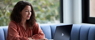 Person using a laptop while seated indoors near a window.