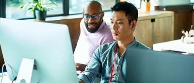 Two persons looking into a desktop screen.