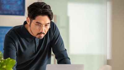 Person leaning over a laptop, focused on work.