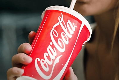 A person sipping a straw in a Coca-Cola cup