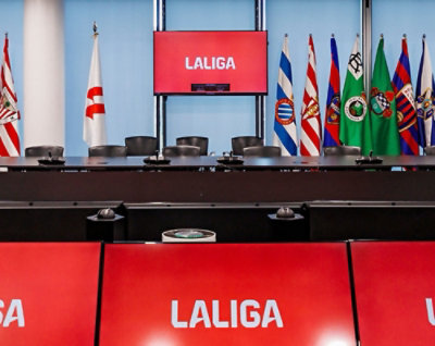 A red sign with white text LALIGA in front of several flags.