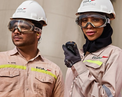 A man and woman wearing hard hats and goggles holding a phone.