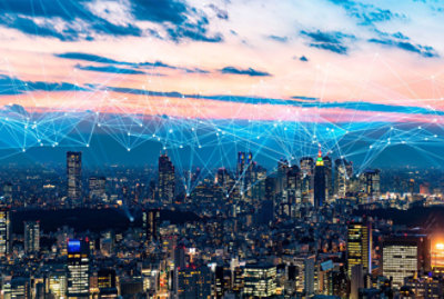 A city skyline at dusk with illuminated buildings and a network of glowing lines connecting different points in the sky above.