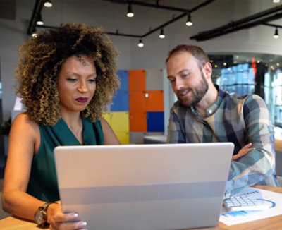Two employees focused on a laptop screen, engrossed in their work.