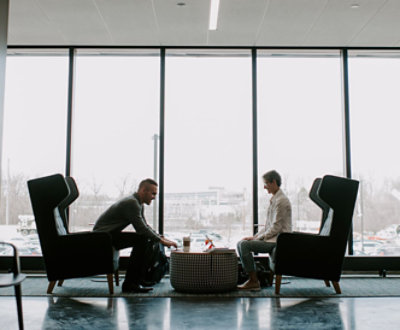 Two people sitting in chairs in front of a large window.