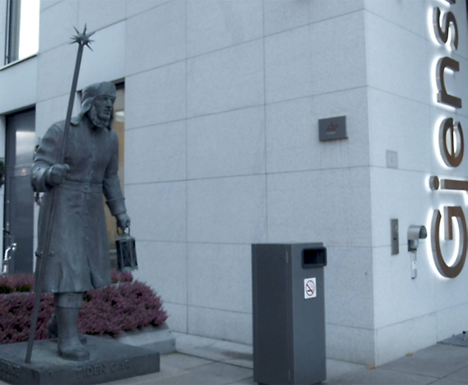 A estátua de um homem em pé na frente de um prédio.