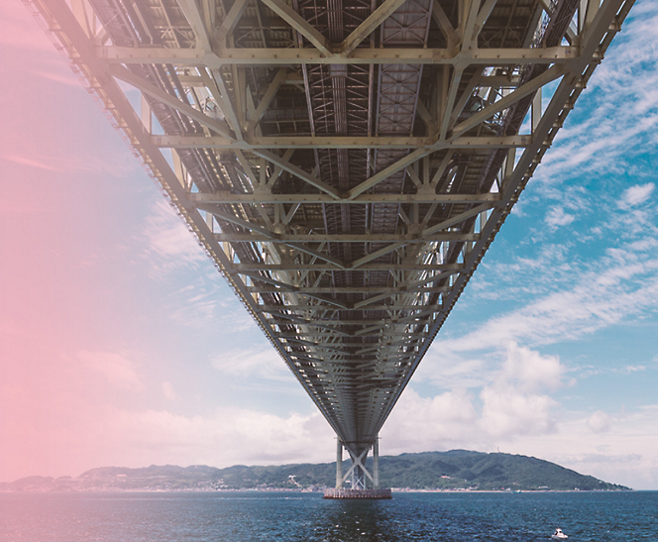 An image of the underside of a bridge under a pink and blue sky.