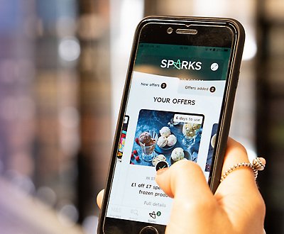En person håller i en telefon som visar Sparks-appen.