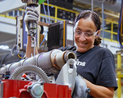 A woman smiling while working on a machine.