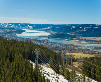En malerisk udsigt over en flod, der snor sig gennem en dal med skove i forgrunden og bjerge i baggrunden,