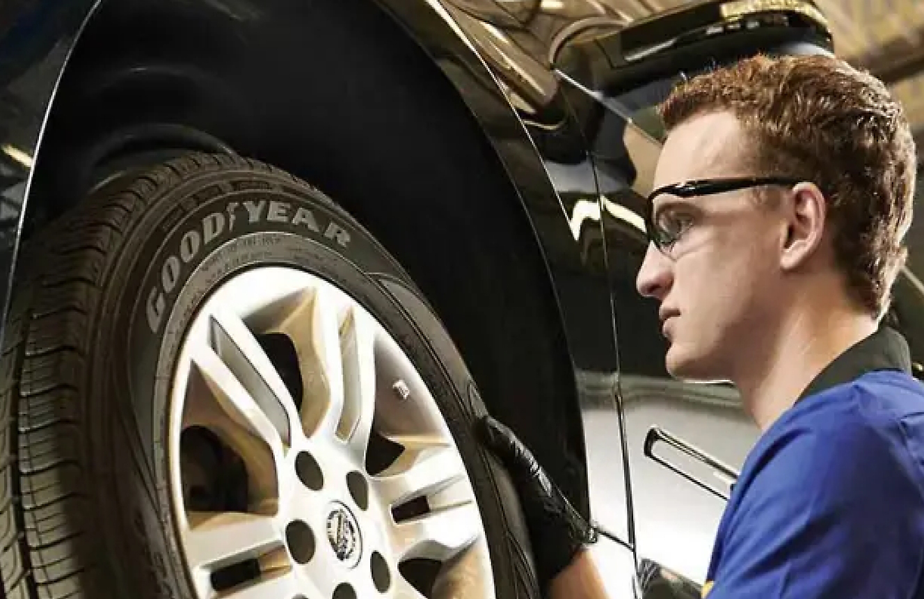 A Goodyear automotive technician installing a wheel on a vehicle