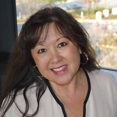 Portrait of a person with long hair, wearing earrings and a light top.