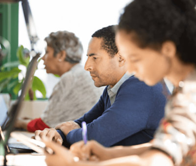 Three person are sitting and looking at desks