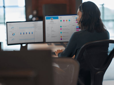 A woman working on desktop with multiple monitors