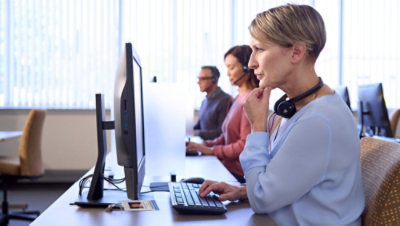 A woman sitting at a desk with a headset on her head.