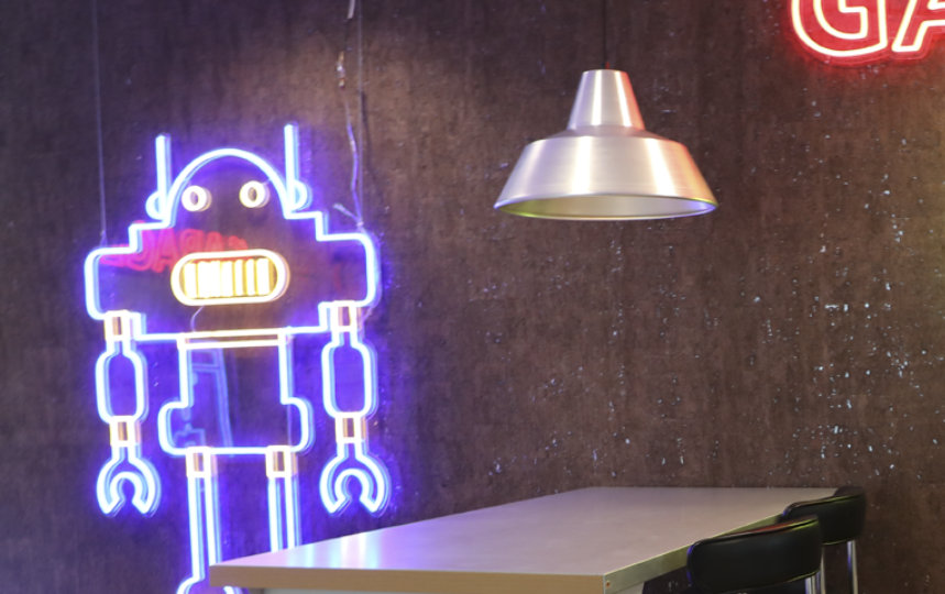 A picture with no persons but two tables and a background with a robot and a ninja cat