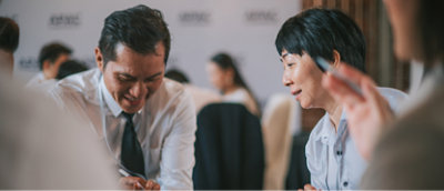Twee personen in zakelijke kleding zijn betrokken bij een discussie en zitten aan een tafel in een vergaderruimte 