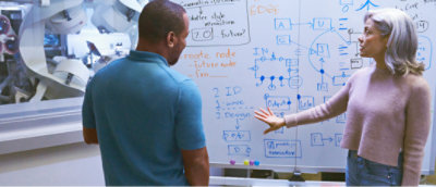 A man and woman standing in front of a whiteboard.