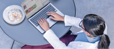 A woman in a white coat using a laptop.