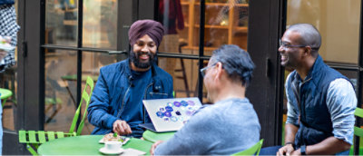 Two men sitting at a table with a laptop.
