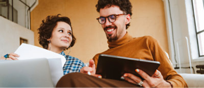 A man and woman looking at a tablet.