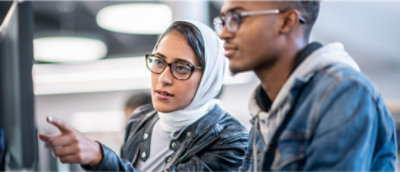 To personer med briller arbejder sammen på en computer.