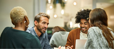 A group of four people are sitting around a table, engaged in conversation.