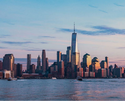 A city skyline at dusk featuring tall buildings with the tallest one in the center