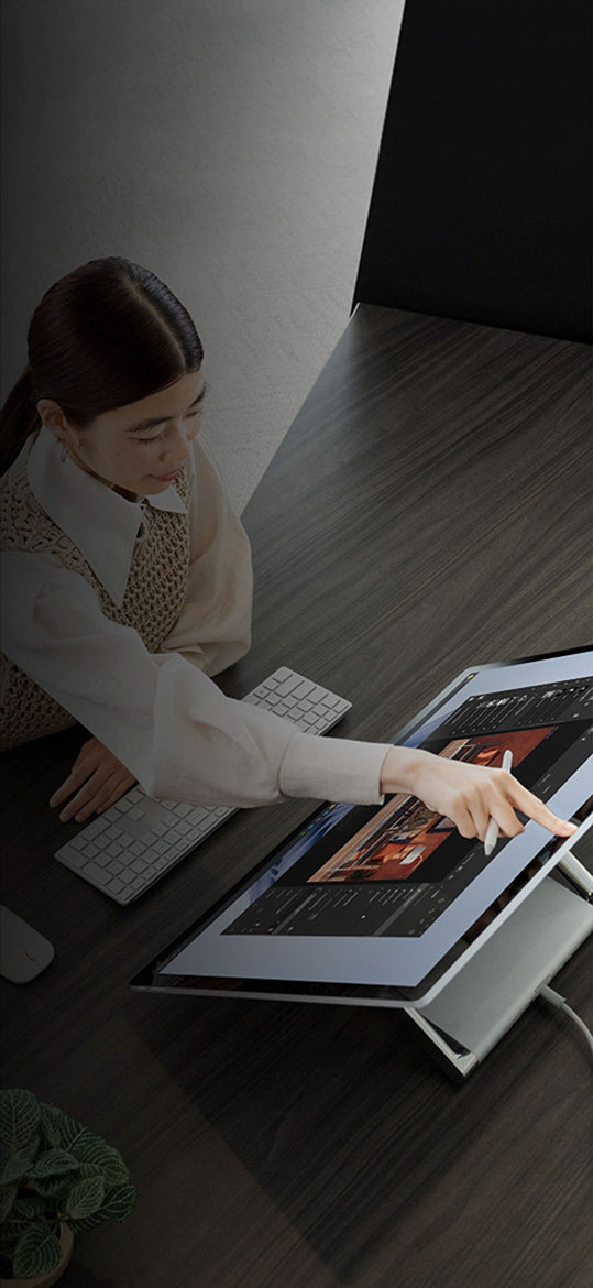 Eine Person tippt bei der Arbeit an einem Surface Studio 2+ mit dem Finger auf Zurück