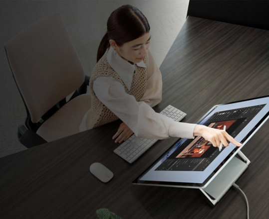 Eine Person tippt bei der Arbeit an einem Surface Studio 2+ mit dem Finger auf Zurück