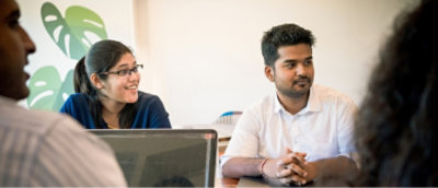 En gruppe personer som sitter ved et bord, er engasjert i en diskusjon. Bakgrunn.