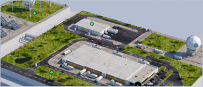 Aerial view of an industrial complex featuring several buildings, parking lots, trucks, grass-covered areas.