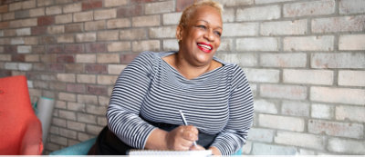 A woman smiling while holding a pen