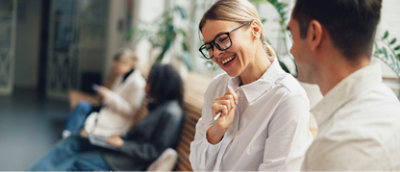 To personer sitter og snakker i forgrunnen. I bakgrunnen sitter to andre personer.