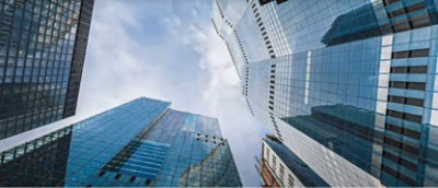 Ser opp mot moderne skyskrapere i glass mot en skyet himmel.