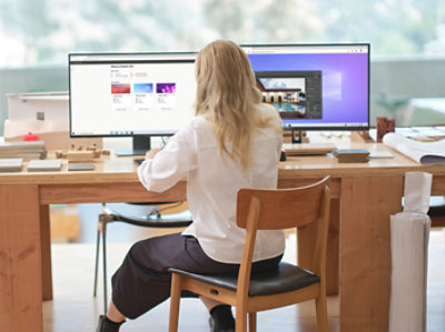 女性がデスクに向かって座り、コンピューター画面を見ています。