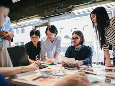 テーブルの周りに座って書類を見ている人々のグループ。
